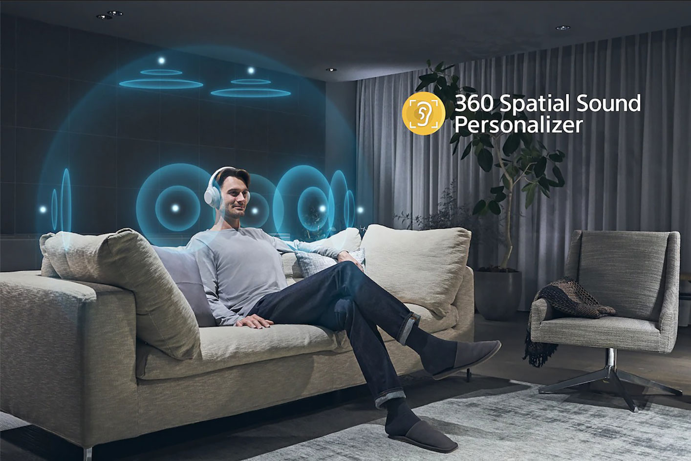 A person sitting on a sofa wearing the ULT WEAR headphones with an annotated display of the Sony | 360 Spatial Sound Personaliser.