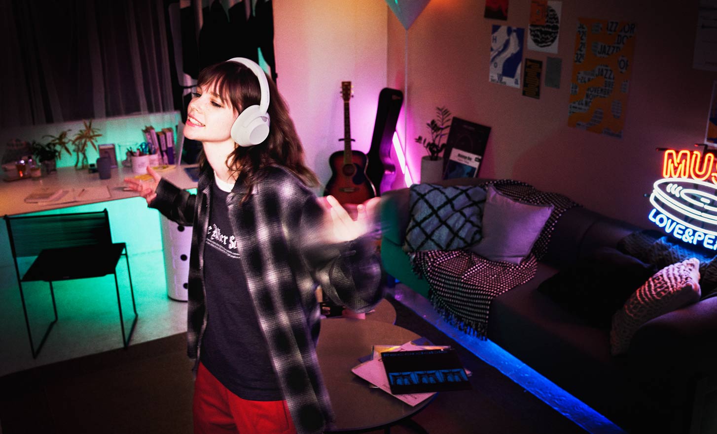 A young person dancing in their home while wearing the WH-ULT900N headphones in white.