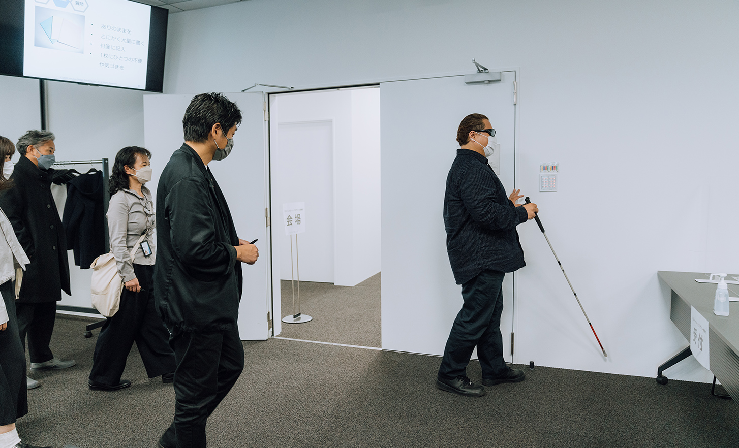 Os funcionários observam o lead user com uma bengala branca a caminhar na sala de conferências