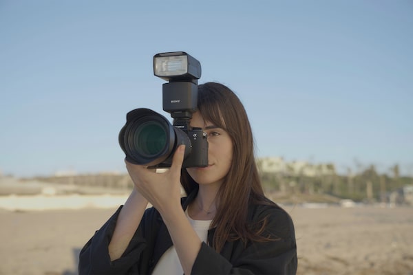 Imagem de utilização de um fotógrafo a segurar numa câmara com um flash externo acoplado